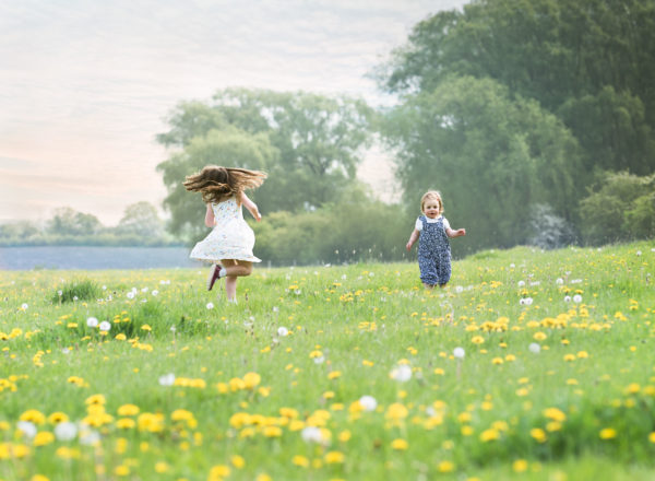 Sisters twirling in a field of dandelions at photoshoot in Wallingford